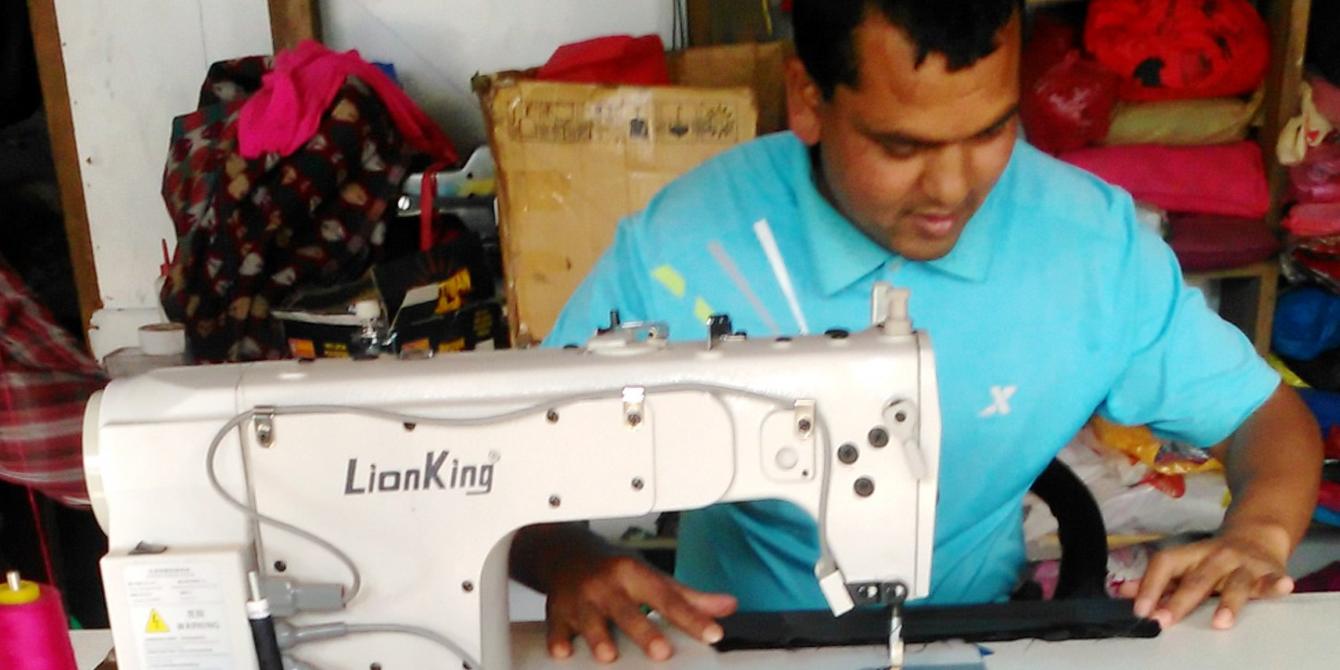 Raju Bishwokarma stitching clothes using his new electric sewing machine. Photo by: Animesh Rai/Oxfam